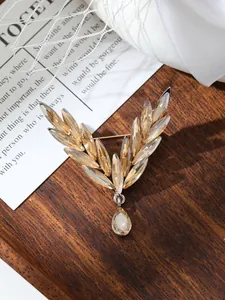 Close-up of a vintage wheat-ear brooch with champagne crystals and a teardrop pendant.