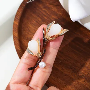 Detail view of elegant magnolia flower brooch with pearl and crystals held by hand