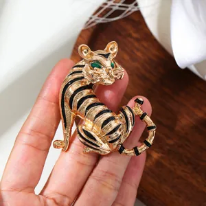 Detailed close-up of a vintage gold tiger brooch with black enamel and green eyes