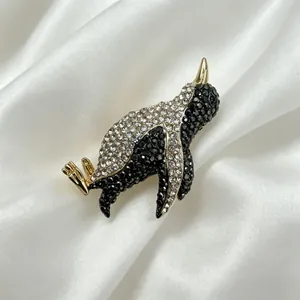 Close-up of a cute sparkling rhinestone penguin brooch on elegant white satin fabric
