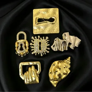 Detailed macro view of vintage gold surrealist brooches on black satin background