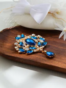 Detailed close-up of a vintage gold-toned brooch with large blue and clear crystals