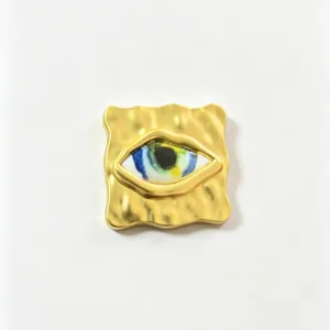 Macro view of gold textured evil eye brooch with colorful artistic iris detail