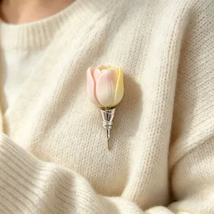 Detailed close-up of a creative tulip brooch pinned on a cream-knit cardigan for women