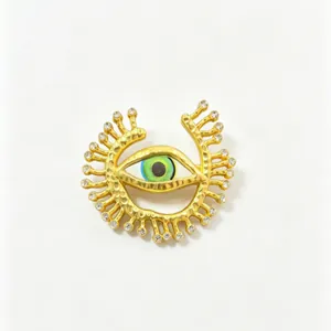 Detailed macro view of an ornate gold evil eye brooch with green iris and crystals