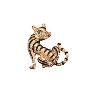 Vintage gold-toned tiger brooch with black enamel stripes and green gemstone eye