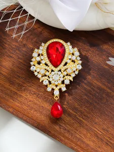 Close-up of a vintage gold-toned brooch with large red teardrop crystals and white rhinestones.