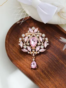 Detailed view of an elegant vintage pink teardrop crystal brooch on a wooden background