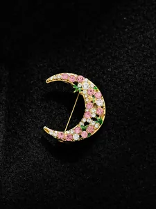 Exquisite detail of a golden crescent moon brooch with pink and white rhinestones inlay