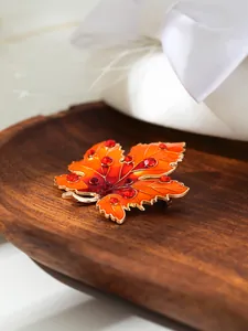 Nahaufnahme einer luxuriösen Ahornblatt-Brosche mit Strass und rotem Emaille-Finish