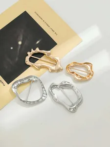 Primo piano di fibbie metalliche irregolari in finiture oro e argento per abiti.