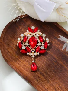 Close-up of elegant red teardrop crystal brooch with intricate gold-tone alloy metalwork.
