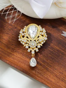 Macro view of vintage gold-toned brooch with large crystal teardrop and rhinestones