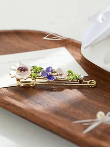 Dettaglio di un'elegante spilla floreale in smalto con tulipani viola e bianchi