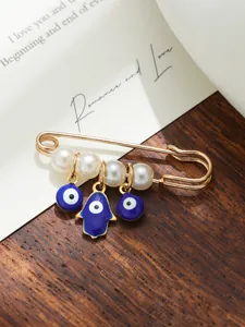 Detailed macro shot of an evil eye and Hamsa hand brooch with pearls on wood