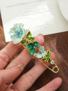 Dettaglio di un'elegante spilla a fiore in smalto con strass su una spilla dorata.