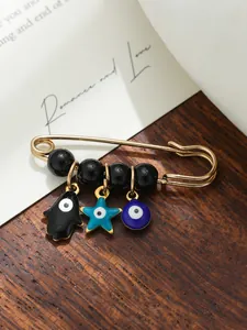 Macro detail of an ethnic gold safety pin brooch with Evil Eye and Hamsa hand charms