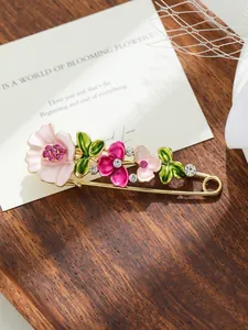 Primo piano di un'elegante spilla floreale con fiori in smalto rosa e cristalli
