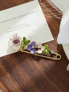 Primo piano di una spilla floreale in smalto con tulipani viola e cristalli lucenti