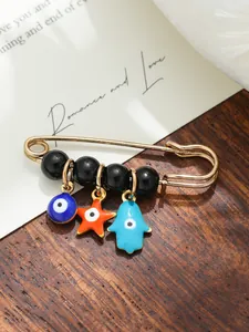 Detail view of ethnic evil eye and hamsa hand charms on a gold-toned safety pin