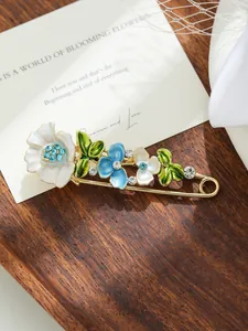 Dettaglio di un'elegante spilla a fiore con petali in smalto e strass scintillanti.