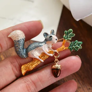 Exquisite close-up detail of a cute squirrel and acorn enamel brooch pin on a branch