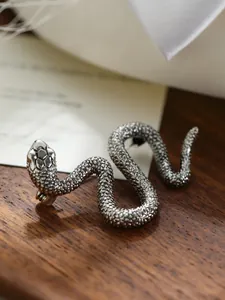 Detalle macro del broche de serpiente de plata antigua con un patrón de escamas realista.