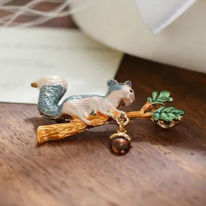 Detailed macro shot of an enamel squirrel and acorn brooch on a golden branch.