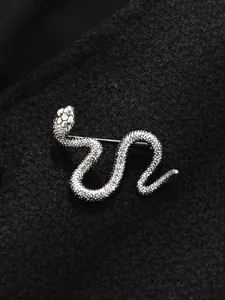 Primer plano de un broche de serpiente plateado con textura en un abrigo de lana negro
