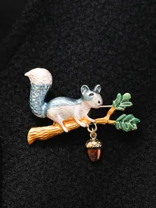 Detailed view of an enamel squirrel brooch with a dangling acorn on a dark coat.