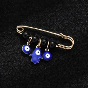 Gold-tone ethnic safety pin brooch featuring blue Evil Eye beads and Hamsa hand charm