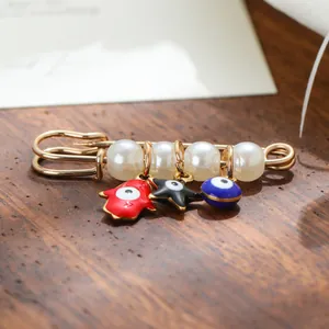 Exquisite evil eye safety pin brooch featuring pearls and colorful ethnic charms on wood