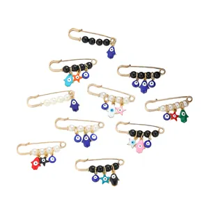 Set of 10 gold-plated evil eye and hamsa hand safety pin brooches with white pearls