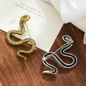 Broche de serpiente vintage detallado en acabados oro y plata sobre fondo madera