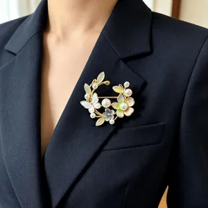 Elegante vintage bloemenkrans broche met parels en kattenoogsteen op een zwarte blazer