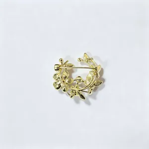 Detail van een vintage gouden bloemenkrans broche met fijne bloemblaadjes en bladeren.