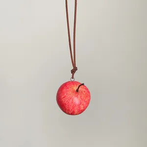 Primer plano de un colgante de manzana roja realista con cordón de cuero marrón