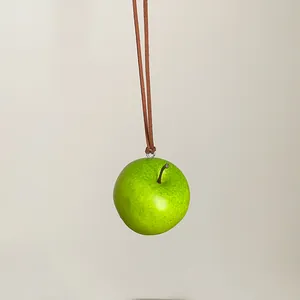 Vista detallada de un collar con colgante de manzana verde realista y cordón de gamuza