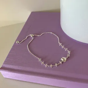 Détail d'un bracelet en argent ajustable avec une boule en métal brossé sur un livre mauve.