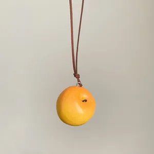 Primer plano de un colgante de manzana amarilla realista en un cordón marrón fino