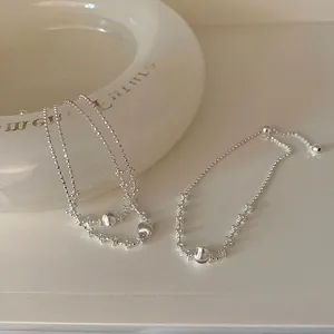 Gros plan de bracelets en perles argentées avec détails de breloques sphériques.