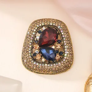 Macro detail of a vintage brooch featuring large red and blue teardrop crystal stones.