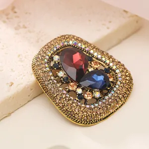 Close-up of vintage gold-tone brooch with red and blue teardrop crystals and rhinestones