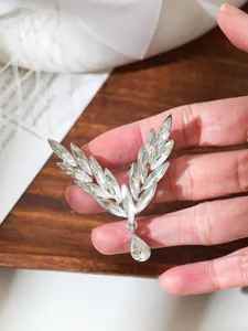Close-up of elegant silver angel wing brooch with clear crystals and teardrop pendant