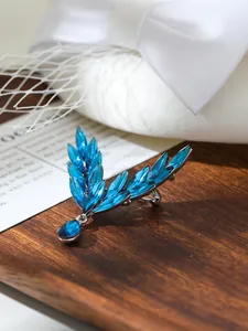 Close-up detail showing sparkling blue marquise-cut crystals on angel wing brooch