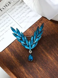 Exquisite close-up of blue crystal angel wing brooch displayed on a rustic wooden tray.