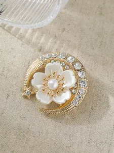 Detailansicht einer eleganten 3D-Blumenbrosche mit Perlen und Strass auf Goldbasis.
