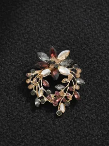 Detailaufnahme einer floralen Strassbrosche mit bunten Kristallen auf schwarzem Stoff