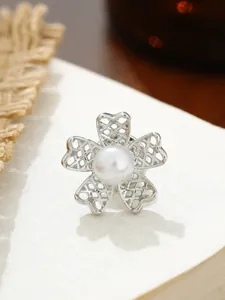 Detaillierte Nahaufnahme einer eleganten silbernen Blumenbrosche mit einer Perle