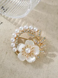 Nahaufnahme einer eleganten goldfarbenen Brosche mit weißen Perlen und Kristallblume